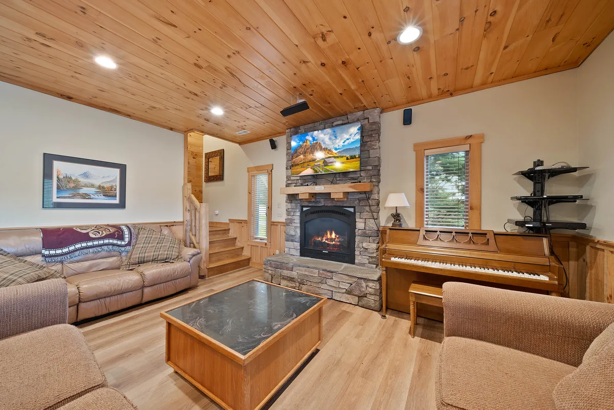 A cozy room comfortably arranged with a fireplace, television, piano, coffee table, and sofas. The layout is perfect for movie nights, music sessions, and intimate socializing by the fire.